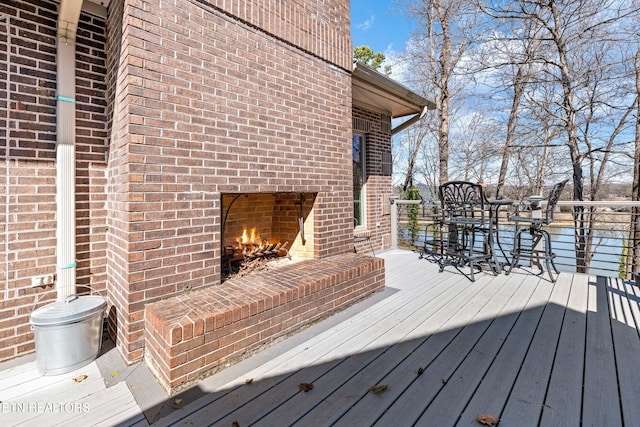 wooden terrace with outdoor dining space and an outdoor brick fireplace