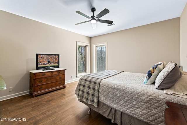 bedroom with visible vents, baseboards, dark wood finished floors, and a ceiling fan