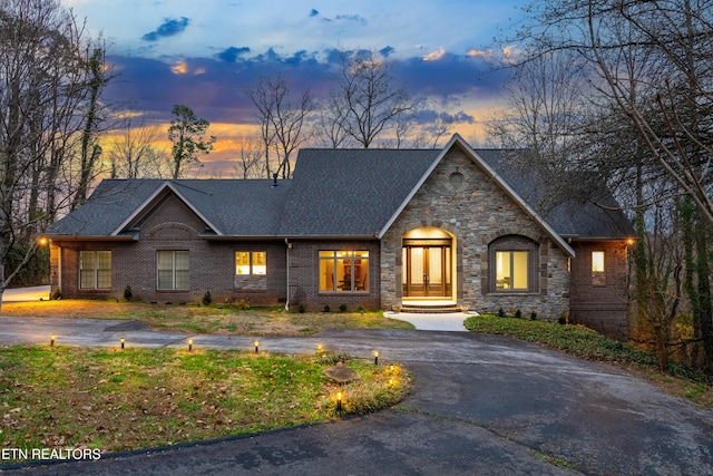 view of front of home featuring brick siding, roof with shingles, and driveway