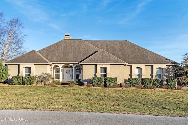 view of front of property with roof with shingles, a chimney, a front lawn, and stucco siding