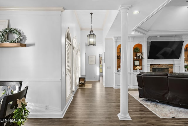 foyer with decorative columns, baseboards, dark wood-style floors, ornamental molding, and a stone fireplace