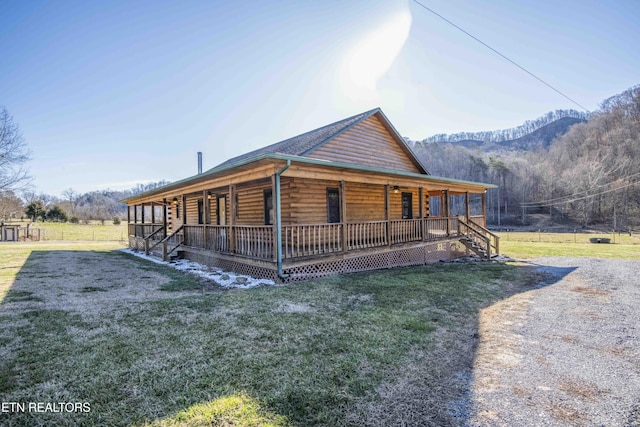 view of side of property featuring covered porch, a mountain view, and a yard