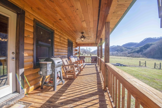 wooden terrace with ceiling fan, a rural view, a mountain view, covered porch, and a grill