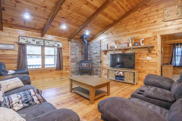 living area with vaulted ceiling with beams, wood ceiling, wood walls, and a wood stove