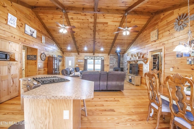 kitchen with light wood-style floors, wood ceiling, a kitchen island, and wooden walls