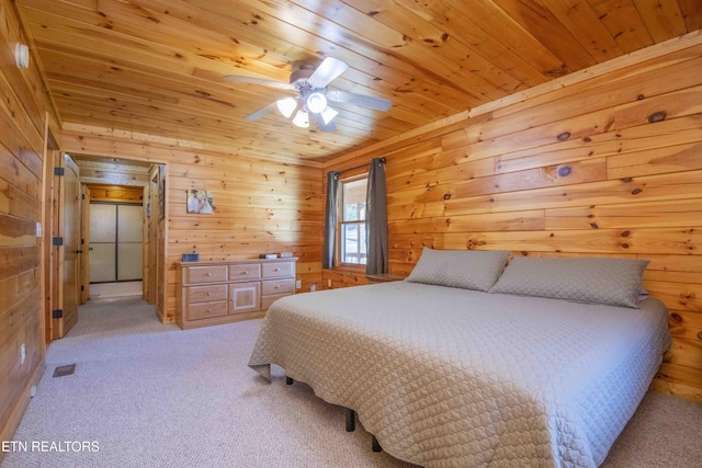 bedroom with wood walls, wood ceiling, and light colored carpet