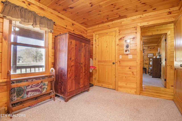 bedroom with wooden ceiling, carpet flooring, and wood walls