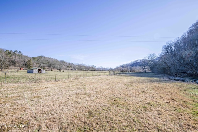 view of yard featuring a rural view, fence, and an outdoor structure