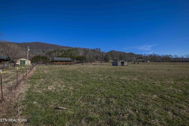 view of yard featuring an outbuilding, a rural view, a view of trees, and a storage unit