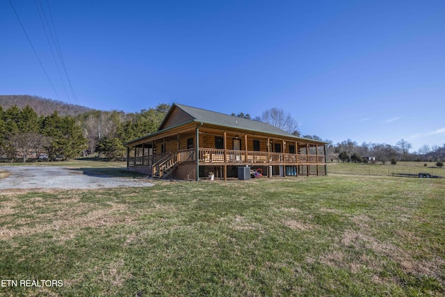 back of property featuring log siding, a porch, and a yard