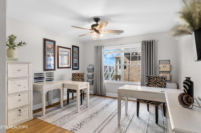 office featuring light wood-type flooring, baseboards, and a ceiling fan