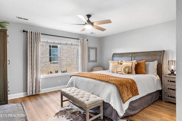 bedroom featuring ceiling fan, visible vents, baseboards, and wood finished floors