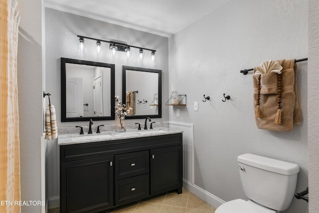 bathroom with tile patterned floors, toilet, double vanity, and a sink