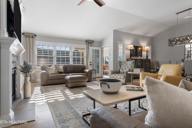 living room with lofted ceiling, a fireplace, wood finished floors, and a ceiling fan