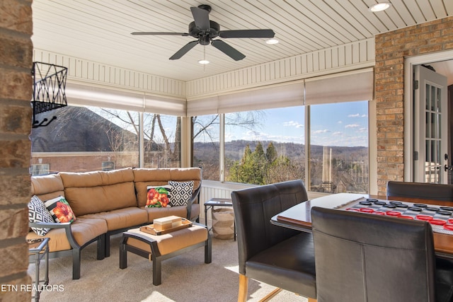 sunroom featuring a wealth of natural light, a mountain view, wood ceiling, and ceiling fan