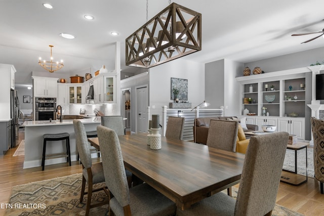 dining room featuring recessed lighting, light wood-style flooring, a fireplace, and ceiling fan with notable chandelier