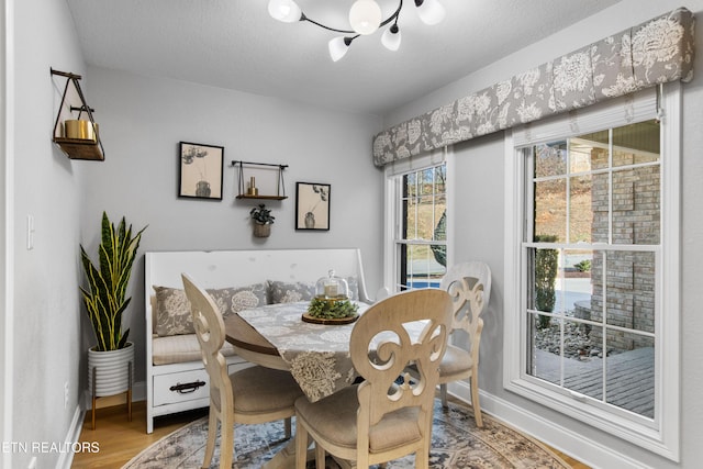 dining room featuring a chandelier, a textured ceiling, baseboards, and wood finished floors