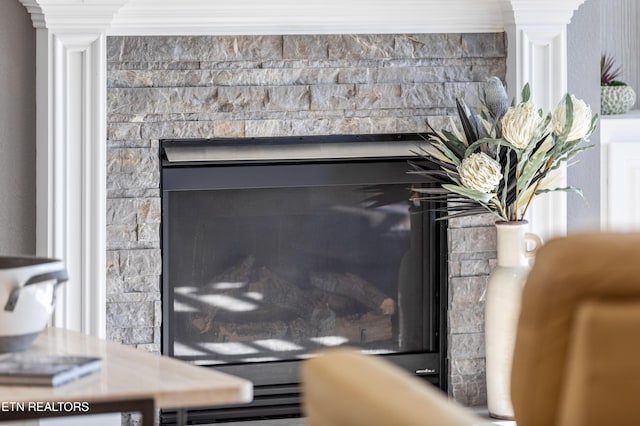 interior details with a stone fireplace and ornamental molding