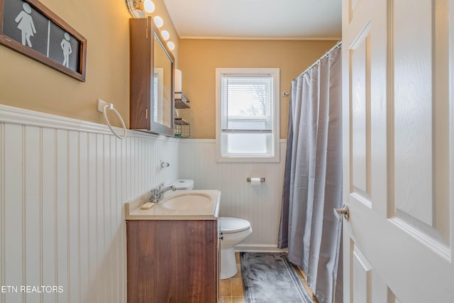 bathroom with a wainscoted wall, toilet, and vanity