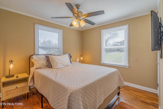 bedroom featuring ceiling fan, wood finished floors, baseboards, and ornamental molding