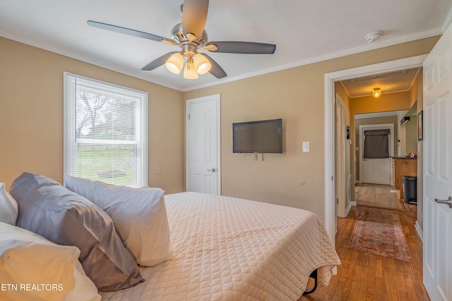 bedroom with wood finished floors, a ceiling fan, and ornamental molding