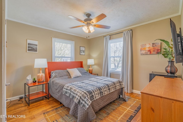bedroom featuring light wood-style flooring, a textured ceiling, crown molding, and baseboards
