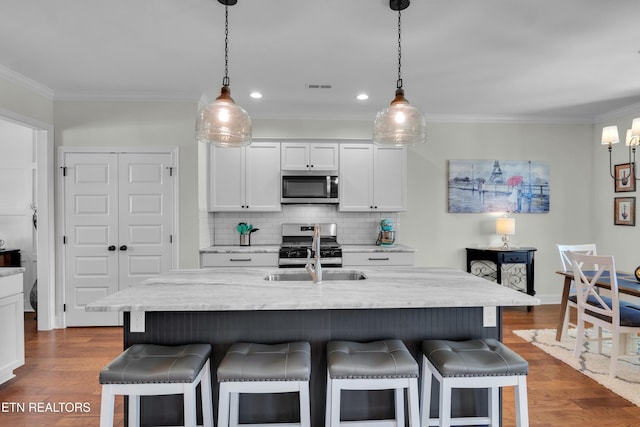 kitchen featuring stainless steel appliances, dark wood finished floors, a sink, and a kitchen breakfast bar