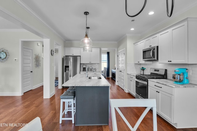 kitchen with dark wood-style floors, appliances with stainless steel finishes, white cabinets, and a sink