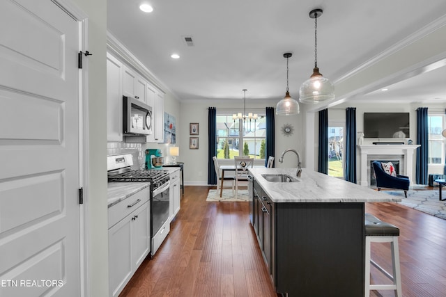 kitchen featuring a sink, a kitchen breakfast bar, open floor plan, ornamental molding, and appliances with stainless steel finishes