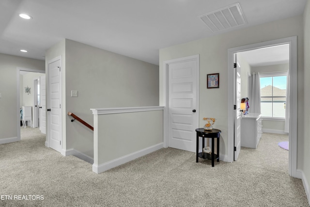 corridor featuring carpet floors, recessed lighting, visible vents, and an upstairs landing