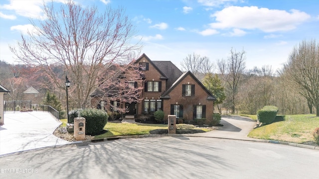 view of front of house featuring brick siding, concrete driveway, and a front lawn