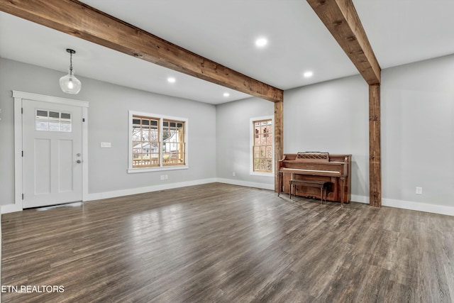 unfurnished living room with beamed ceiling, wood finished floors, and baseboards