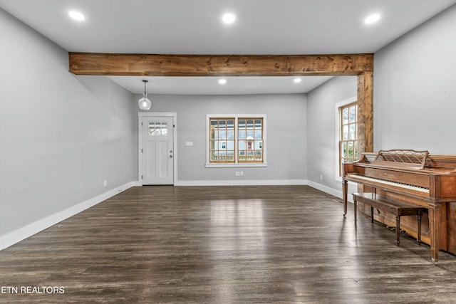 interior space with beamed ceiling, baseboards, and wood finished floors