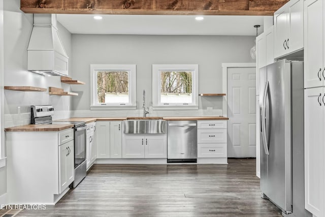 kitchen with a sink, open shelves, butcher block counters, and stainless steel appliances