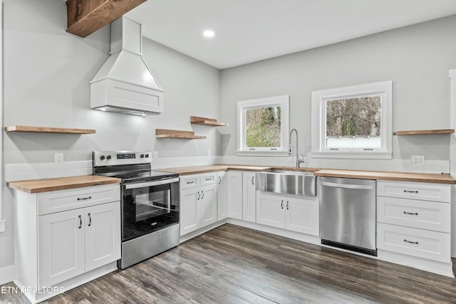 kitchen with wooden counters, open shelves, appliances with stainless steel finishes, custom exhaust hood, and dark wood-style flooring