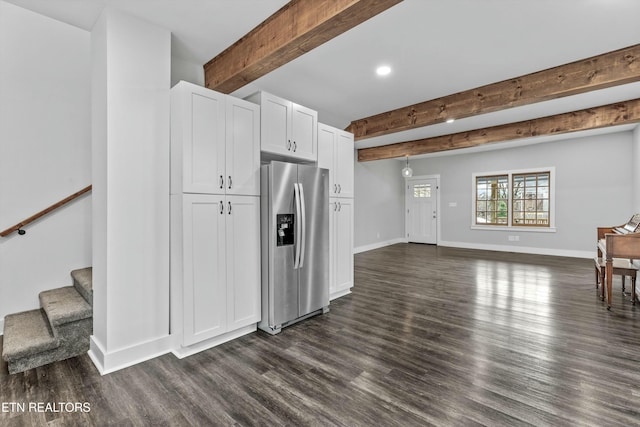 kitchen featuring dark wood-type flooring, baseboards, beamed ceiling, white cabinets, and stainless steel fridge