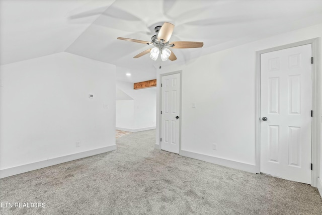 empty room with vaulted ceiling, carpet flooring, a ceiling fan, and baseboards