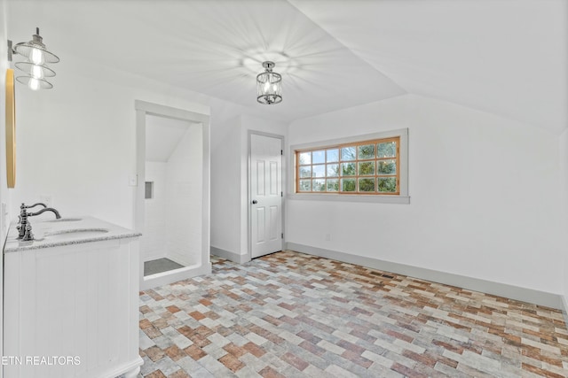 interior space featuring baseboards, lofted ceiling, and a sink