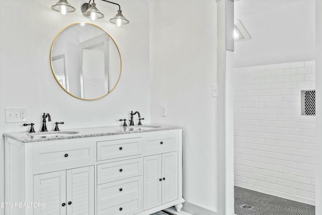 bathroom featuring a sink, tiled shower, and double vanity