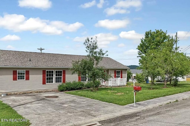 ranch-style house with driveway, a front lawn, and roof with shingles