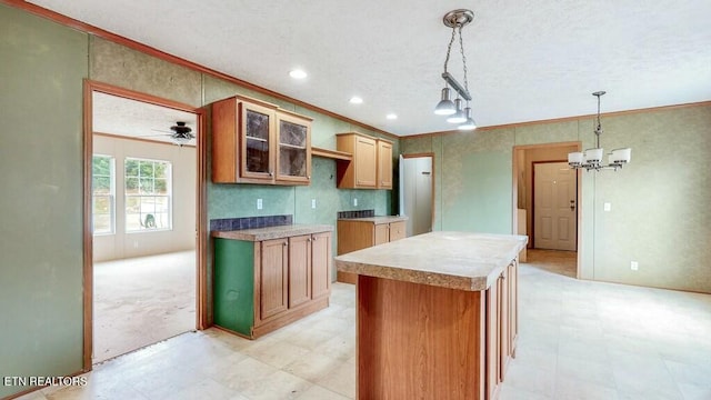 kitchen featuring glass insert cabinets, decorative light fixtures, a center island, crown molding, and light floors