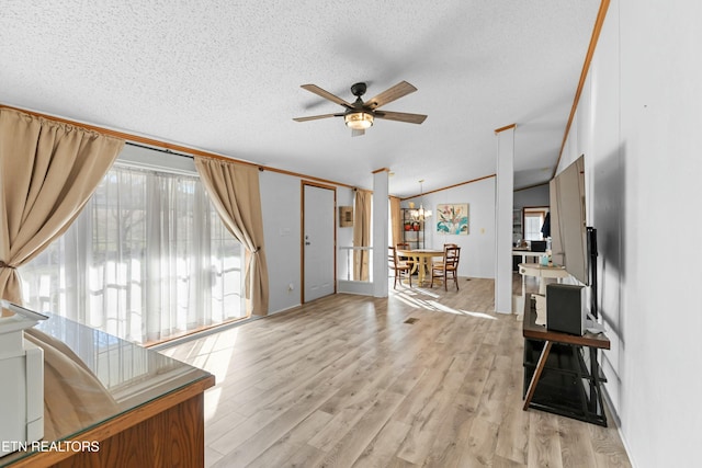 living room with light wood finished floors, vaulted ceiling, a textured ceiling, and ceiling fan with notable chandelier