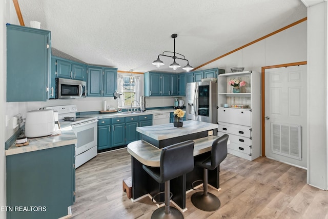 kitchen with lofted ceiling, visible vents, appliances with stainless steel finishes, a sink, and blue cabinets