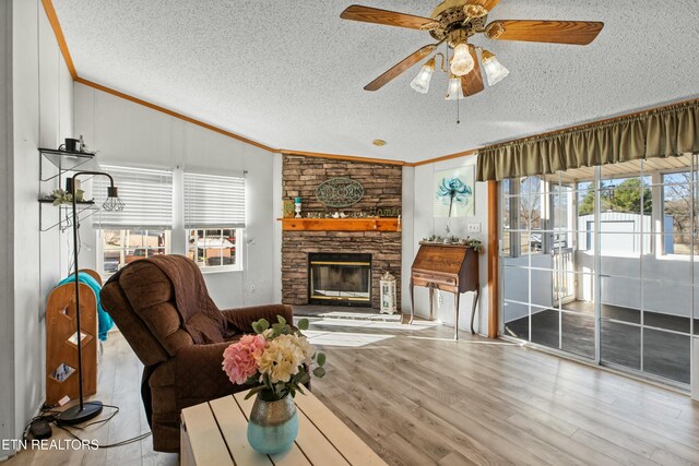 living area with lofted ceiling, a textured ceiling, ornamental molding, and wood finished floors