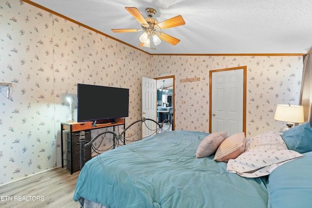 bedroom with ceiling fan, ornamental molding, wood finished floors, and wallpapered walls