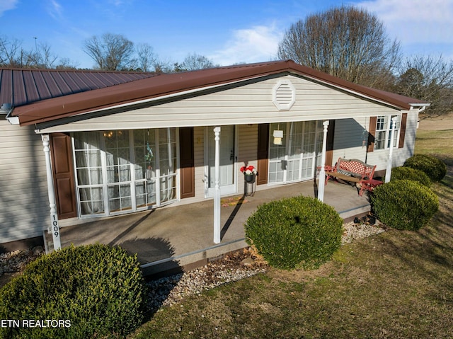 back of house featuring a porch and metal roof