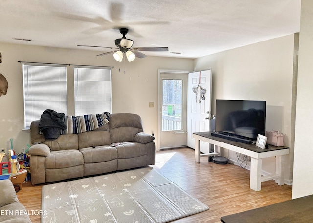 living room with ceiling fan, wood finished floors, and visible vents