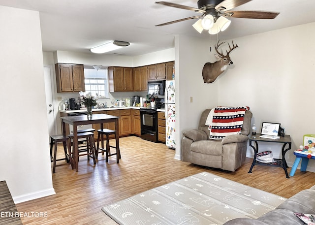 kitchen with black appliances, light wood-type flooring, light countertops, and baseboards