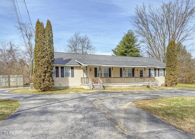 single story home featuring driveway, fence, a porch, and roof with shingles