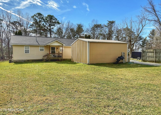 back of property with an outbuilding, a yard, and fence